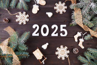 2025 rakamları, köknar dalları ve kozalaklarla kaplı, organik maddelerden yapılmış çevre dostu bir dekor. Mutlu yıllar 2025 ve mutlu Noeller. Üst görünüm