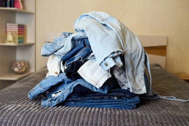 Yatağın üstünde kot elbise yığını var..