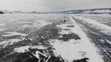Arabalar Baykal Gölü 'nün buzundan Olkhon Adası' na uçuyor, hava manzaralı. Kış gezisi. 