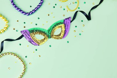 Mardi Gras festivali için boncuklu ve köpüklü yeşil bir arka planda renkli bir karnaval maskesi. Üst görünüm, alanı kopyala.