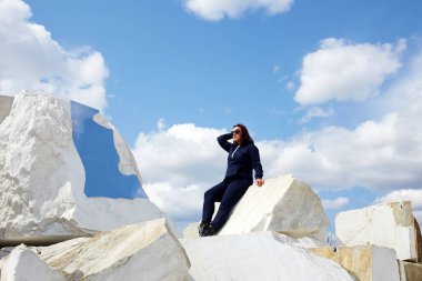 Bir kadın büyük beyaz mermer blokların üzerinde duruyor. Terk edilmiş bir mermer ocağı. Buguldeika köyü yakınlarında popüler bir turizm merkezi..