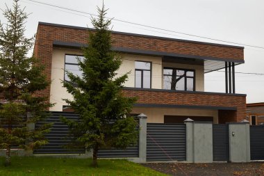 Tuğla ve diğer malzemelerden yapılmış iki katlı modern bir ev..