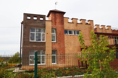 Benzersiz mimarisi ve geniş bahçesi olan modern tuğla ev bir banliyö mahallesinde yer alıyor..