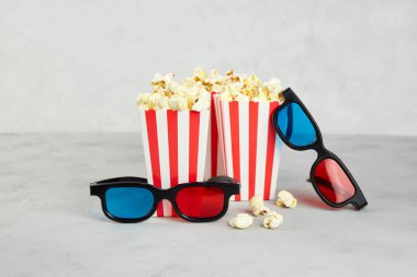 Patlamış mısır, gri arka planda sinema saati için 3D gözlükler.. 