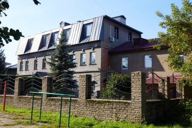 Modern mimari özelliklere sahip iki farklı bina ve açık mavi gökyüzünün altında bir yerleşim bölgesinde iyi korunmuş bir bahçe..