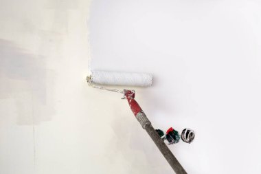 Gündüz vakti kısmen yenilenmiş bir odada silindirle duvar boyamak..