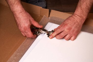 Kapıya bir mobilya menteşesi takmak. Mobilya montajı ve tesisat tamiri. Erkekler mobilyaları dolap kapısına yerleştirirler.. 