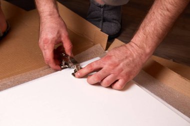 Erkekler mobilya menteşesini dolap kapısına sokarlar. Kapıya bir mobilya menteşesi takmak. Mobilya montajı ve montajı. 