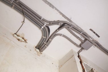 Koruyucu kablo tüpündeki elektrik kabloları, bağlantı kutusu düzgünce tavana yerleştirilmiş. Tamir odasına elektrik tesisatı kurulumu.