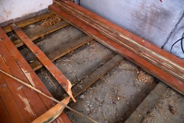 İç mekan kısmen soyulmuş ahşap bir zemin gösteriyor. Altında ahşap boncuklar ve açık toprak var.. 