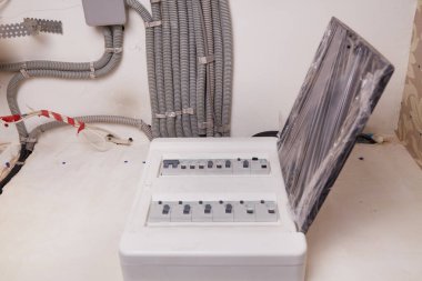 Tavanda koruyucu kıvrımlı bir borudaki elektrik kabloları ve duvardaki modüler evler. Bir odaya yenilenen elektrik kablolarının kurulumu.