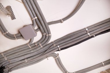 Koruyucu kablo tüpündeki elektrik kabloları ve bağlantı kutusu düzgünce tavana yerleştirilmiş. Tamir odasına elektrik tesisatı kurulumu.