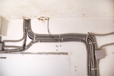 Koruyucu kablo tüpündeki elektrik kabloları ve bağlantı kutusu düzgünce tavana yerleştirilmiş. Tamir odasına elektrik tesisatı kurulumu.