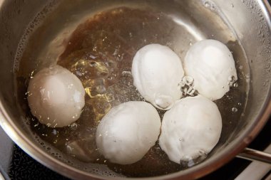 Haşlanmış yumurta. Metal tencerede kaynamış suda tavuk beyazı yumurtalar.. 