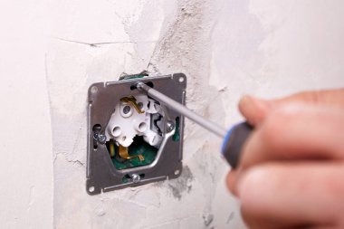 Elektrikçi tornavida kullanarak duvara elektrik prizi takıyor. Daire tadilattan geçiyor..