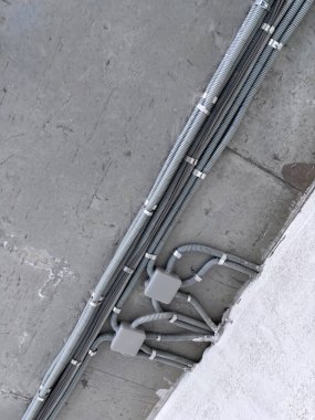 Koruyucu kablo tüpündeki elektrik kabloları ve bağlantı kutusu düzgünce tavana yerleştirilmiş. Tamir odasına elektrik tesisatı kurulumu.