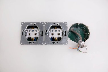 Duvara kablolar için yapılmış üç elektrik kutusu var ve bir tanesinden internet kablosu çıkıyor. Soketleri kurmak için çalışmalar sürüyor.