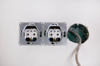 Duvarda kablolar için inşa edilmiş üç elektrik kutusu var ve bir tanesinden kablolar çıkıyor. Soketleri kurmak için çalışmalar sürüyor.