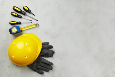 İşçi bayramınız kutlu olsun. İnşaat aletleri, sarı kask, gri arkaplan mezurası, kopyalama alanı. Üst görünüm