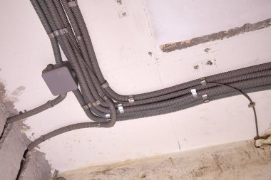Koruyucu kablo tüpündeki elektrik kabloları ve bağlantı kutusu düzgünce tavana yerleştirilmiş. Tamir odasına elektrik tesisatı kurulumu.