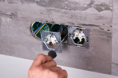 Ev elektriği tamiri devam ediyor. Duvardaki aletler ve kablolarla birlikte. Elektrik prizlerinin kurulumu