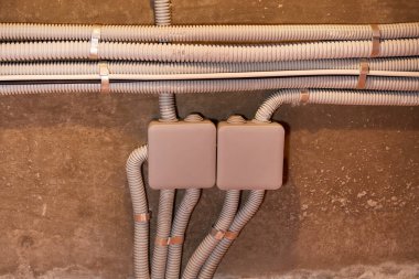 Koruyucu kablo tüpündeki elektrik kabloları ve bağlantı kutusu düzgünce tavana yerleştirilmiş. Tamir odasına elektrik tesisatı kurulumu.