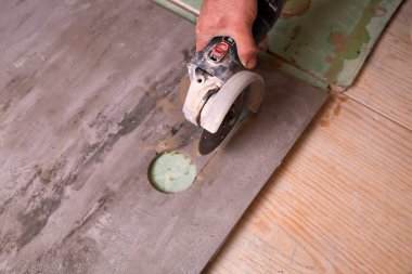 Yetenekli eller, gün ışığında bir ev atölyesinde tadilat sırasında granit fayanslar kesiyor..