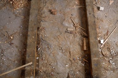 Beton zeminde tozlu ahşap kirişler enkaz ve talaşla kaplı. Tamir süreci, eski ahşap zeminin kaldırılması.. 
