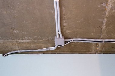 Koruyucu kablo tüpündeki elektrik kabloları ve bağlantı kutusu düzgünce tavana yerleştirilmiş. Tamir odasına elektrik tesisatı kurulumu.