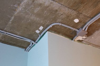 Koruyucu kablo tüpündeki elektrik kabloları ve bağlantı kutusu düzgünce tavana yerleştirilmiş. Tamir odasına elektrik tesisatı kurulumu.