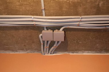 Koruyucu kablo tüpündeki elektrik kabloları ve bağlantı kutusu düzgünce tavana yerleştirilmiş. Tamir odasına elektrik tesisatı kurulumu.