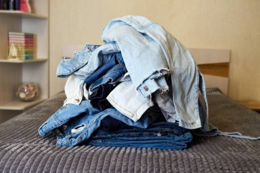 Yatağın üstünde kot elbise yığını var..