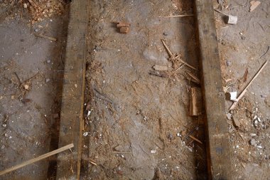 Beton zeminde tozlu ahşap kirişler enkaz ve talaşla kaplı. Tamir süreci, eski ahşap zeminin kaldırılması.. 