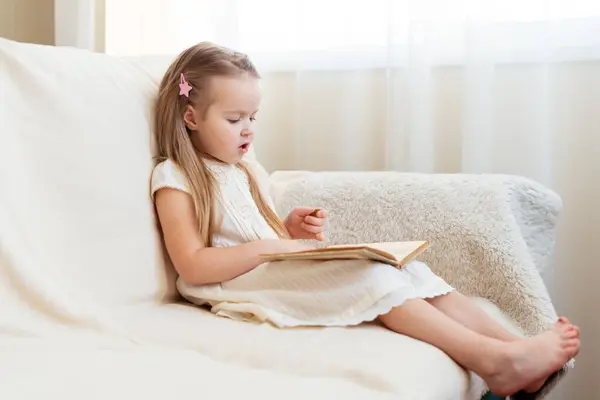 Маленькая Симпатичная Блондинка Читает Книгу Сидя Диване Детское Чтение Сновидения — стоковое фото