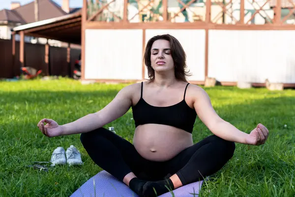 孕妇在院子里做瑜伽 在草地上沉思 深呼吸 呼吸新鲜空气 做瑜伽莲花 姿势舒适 瑜伽母性 心理健康和怀孕概念 — 图库照片