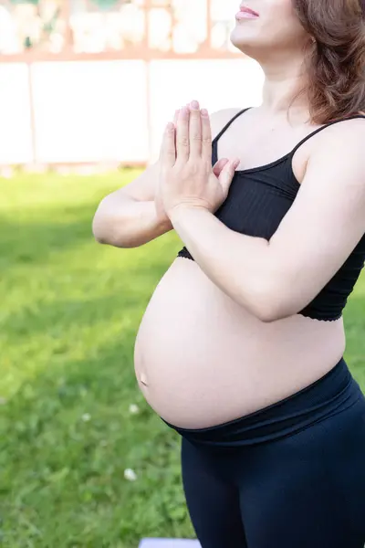 Pregnancy woman breathing and calm with yoga outdoor, doing stretching exercise on grass. Self Care, Yoga, Pregnant, Maternity Concept. Enjoy motherhood, health care, hobbies.