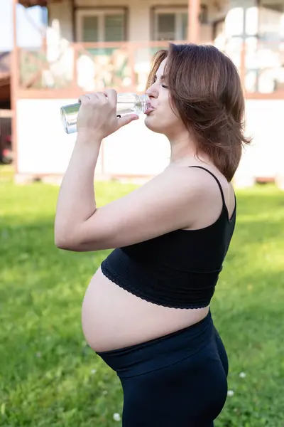 参加体育运动的孕妇在户外运动后喝了一瓶水 在瑜伽练习 健身和冥想中休息 精神健康和怀孕概念 — 图库照片