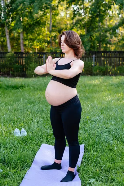 Pregnancy woman breathing and calm with yoga outdoor, doing stretching exercise on grass. Self Care, Yoga, Pregnant, Maternity Concept. Enjoy motherhood, health care, hobbies.