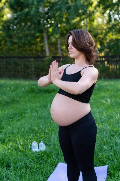 怀孕妇女呼吸平静 在室外使用瑜伽 在草地上做伸展运动 自我照顾 母性概念 享受母性 医疗保健 业余爱好 — 图库照片