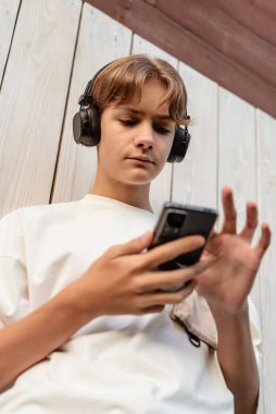 Akıllı telefonlara bakan ve dışarıda sohbet eden, telefonla konuşan, yazan, telefonla mesaj okuyan, çocuk ve akıllı telefon kullanan, sosyal medyaya, internet işine bakan genç bir çocuk.