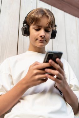 Akıllı telefonlara bakan ve dışarıda sohbet eden, telefonla konuşan, yazan, telefonla mesaj okuyan, çocuk ve akıllı telefon kullanan, sosyal medyaya, internet işine bakan genç bir çocuk.