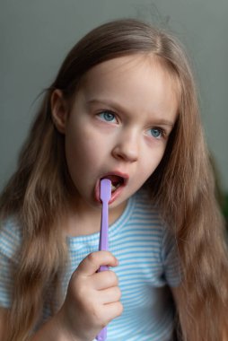 Kafkasyalı genç bir kız mor diş fırçasıyla dişlerini fırçalıyor..