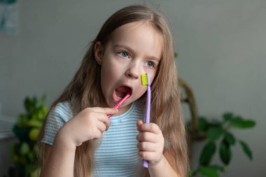 Beyaz çocuk renkli diş fırçalarıyla dişlerini fırçalıyor..