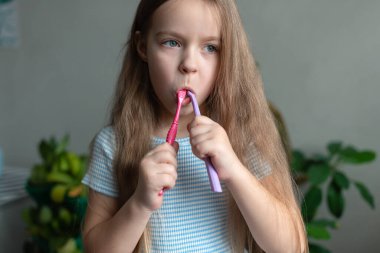 Banyoda diş fırçasıyla diş fırçalayan beyaz bir genç kız..