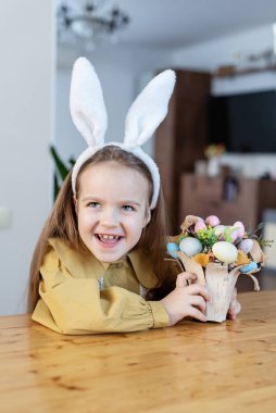 Tavşan kulaklı genç beyaz kız Paskalyayı renkli yumurta düzenlemesiyle kutluyor..