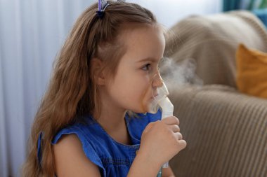 Beyaz kız evde solunum tedavisi için nebulizör kullanıyor..