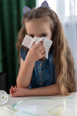 Kafkasyalı genç bir kız peçeteye hapşırıyor. Pofuduk kedi kulaklığıyla..