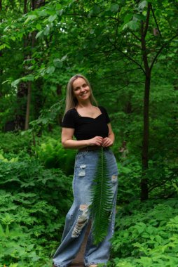 Ormanda eğreltiotu yaprağı ve sıkıntılı kotu olan beyaz bir kadın..