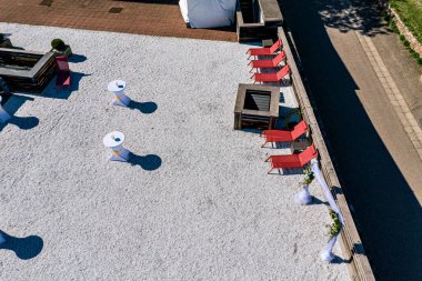 Güneşli terasın en üst manzarası. Güneş pansiyonları ve açık büfe masaları. Sert gölgeler. Gün ortası güneşi.