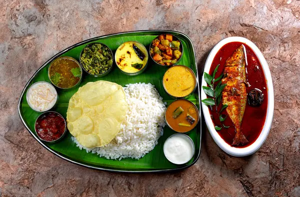 Kerala fish curry meals. Traditional South Indian meal served on a banana leaf with rice, curry, vegetables, papadum, and a side of fish, showcasing vibrant colors and rich culinary culture.
